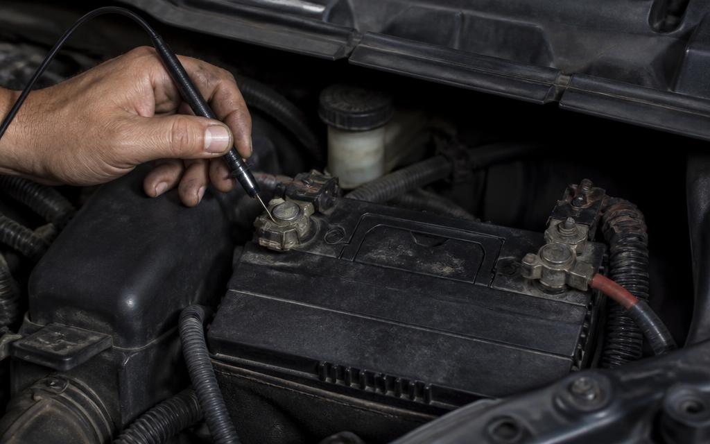 Car battery and wiring in an engine bay with a terminal clamp being fitted
